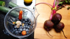 Fruits in an open blender with beets in the background.