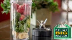 A cup filled with fruit and spinach on a table.
